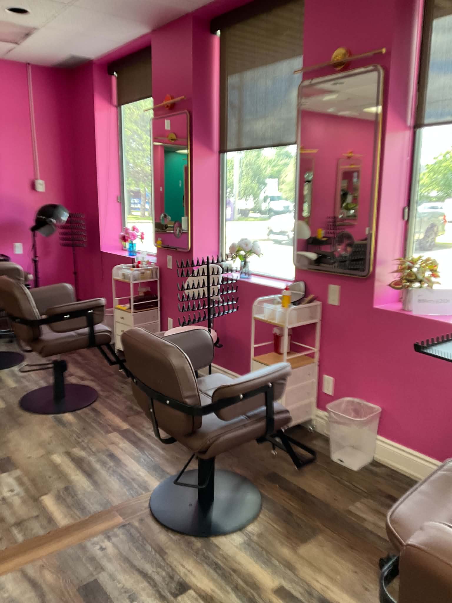 Braiding stations with chairs, mirrors, and hair racks by the windows